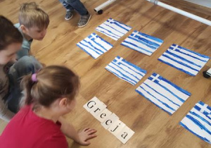 Dzieci układają kolejne litery aby ułożyć napis Grecja.